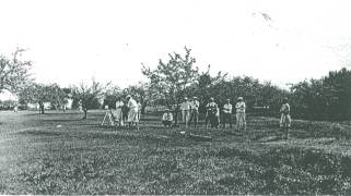 Players teeing off on the original #1 tee. A fruit tree orchard bordered the course in those days.